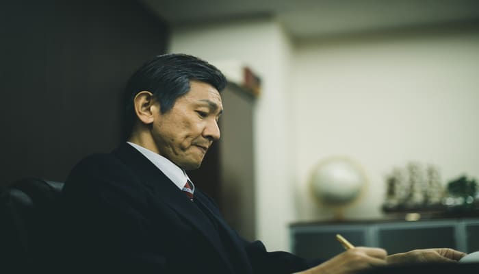 書類を作成する経営者